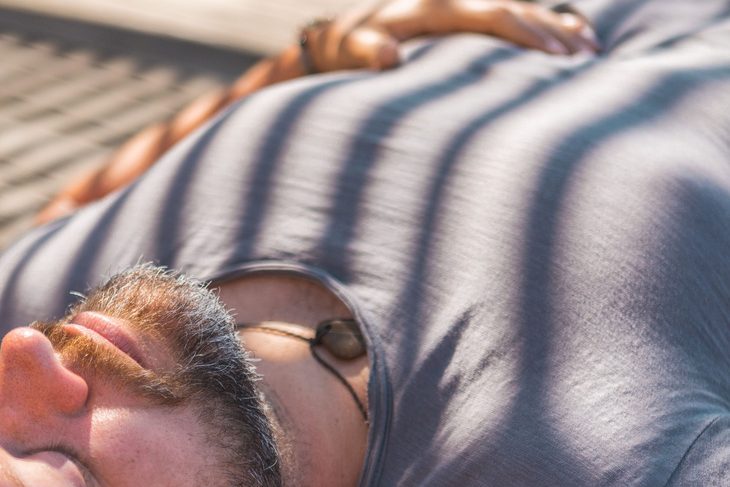 Mann liegt entspannt in der Sonne und atmet ruhig
